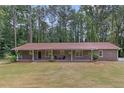 Charming brick home with a covered front porch and well-maintained lawn with mature trees in the background at 6372 Valley Dale Dr, Riverdale, GA 30274
