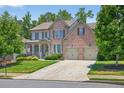 Charming brick home with manicured lawn, inviting porch, and a two-car garage at 5740 Zelkova Dr, Cumming, GA 30040