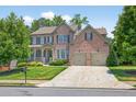 Lovely brick home featuring a two-car garage, lush lawn, and mature trees at 5740 Zelkova Dr, Cumming, GA 30040