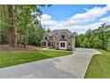 View of a long concrete driveway leading to a two-story brick home surrounded by lush trees at 7449 Waterview Cv, Douglasville, GA 30135