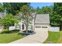 Charming two-story home with a manicured lawn, mature trees, a paved driveway, and an attached two-car garage at 1095 Northpoint Trce, Roswell, GA 30076
