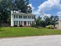 Traditional two-story house with black shutters, red door and lush green lawn on a sunny day at 1725 Spindle Top Sw Ct, Lilburn, GA 30047