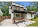 Stylish two-story home with a white brick exterior, sleek lines, and a covered porch, surrounded by mature trees at 1355 Lockwood Sw Dr, Atlanta, GA 30311