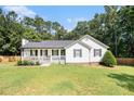 Charming single-story home featuring a cozy front porch, green lawn and landscaped garden at 136 Fairlane Dr, Covington, GA 30016