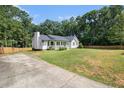 Quaint home featuring a well-manicured lawn, inviting front porch, mature trees, and long driveway at 136 Fairlane Dr, Covington, GA 30016