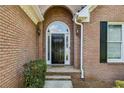 Elegant arched front door with sidelights, set within a classic brick facade, enhances the home's entry at 1506 Threepine Place Pl, Lilburn, GA 30047