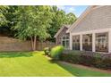 The landscaped backyard features a retaining wall, lush lawn, and vibrant greenery around the home at 6042 Brookhaven Cir # 3202, Johns Creek, GA 30097