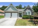 Well-kept home featuring a stone facade, two-car garage, manicured lawn, and bay window at 1856 Temple Park Dr, Loganville, GA 30052