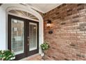 Elegant front door with glass panels and a decorative light fixture on a classic brick facade at 2584 Oglethorpe Ne Cir, Brookhaven, GA 30319