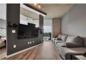 Open concept living room featuring hardwood floors, concrete ceilings, a large TV, and a comfortable grey couch at 361 17Th St # 1121, Atlanta, GA 30363