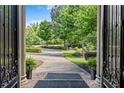 Inviting entrance featuring a long driveway framed by lush landscaping and elegant iron gate accents at 55 Moray Pl, Covington, GA 30014