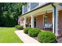 Inviting covered front porch with white columns, charming bench seating, and beautifully landscaped bushes at 1642 Reflections Trl, Powder Springs, GA 30127