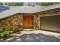 Exterior with stone facade and wooden double door entry and attached garage at 562 Pine Valley Se Rd, Marietta, GA 30067