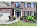 Close-up of the home's entrance, highlighting the black door, white columns, and colorful landscaping at 127 Bradshaw Park Dr, Woodstock, GA 30188