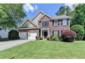 Charming two-story brick home with a well-manicured lawn, two-car garage, and beautifully landscaped front yard at 127 Bradshaw Park Dr, Woodstock, GA 30188