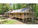 View of a stone-clad ranch style home with a wraparound porch nestled in a forest setting at 257 Martin Ln, Canton, GA 30114