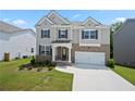 Charming two-story home with gray siding, stone accents, well-manicured lawn, and attached two-car garage at 865 Athena Bnd, Fairburn, GA 30213