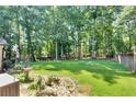 Spacious backyard featuring a lush lawn, mature trees offering shade, and plenty of room for outdoor activities at 1481 Howard Way, Lawrenceville, GA 30043