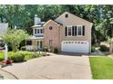 Traditional-style home with a brick facade, two-car garage, complemented by mature trees and a well-kept lawn at 1481 Howard Way, Lawrenceville, GA 30043