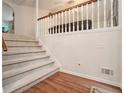 Cozy staircase with carpeted steps, a wooden railing, and hardwood floors below at 304 Bennett Farms Ct, Acworth, GA 30102
