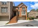 Inviting brick townhouse with a front-facing garage, and a welcoming front porch with stairs at 5575 Julian Pl, Atlanta, GA 30342