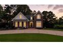 Inviting brick home with a manicured lawn, circular driveway, and warm lighting at dusk at 2845 Burgundy Dr, Cumming, GA 30041