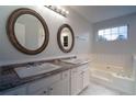Elegant bathroom with dual sinks, round mirrors, and a soaking tub, providing a relaxing and luxurious experience at 2333 Wilkins Cv, Decatur, GA 30035