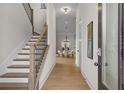 Inviting entryway with hardwood floors, staircase, and view of the dining room with modern chandelier at 89 Batten Board Way, Woodstock, GA 30189