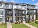 Exterior view of townhome with multiple balconies, green lawn and landscaping at 505 Hampton Crossing, Woodstock, GA 30188