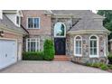 Grand brick home featuring a stone facade, arched windows, and a paved driveway at 8230 Royal Melbourne Way, Duluth, GA 30097