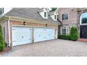 Spacious two-car garage with white doors and a lovely brick-paved driveway at 8230 Royal Melbourne Way, Duluth, GA 30097