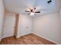 A cozy bedroom with wood floors, ceiling fan, and white closet doors at 1282 Harris Commons Pl, Roswell, GA 30076
