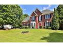 Beautiful two-story brick home with a lush green lawn and mature trees in a suburban setting at 3520 Mystic Dr, Buford, GA 30519