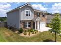 Side view of a two-story home with vinyl siding, landscaping, and a two-car attached garage at 3660 Cattle Field Xing, Loganville, GA 30052