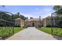Elegant home with an ornate iron gate, a long driveway, and a beautifully landscaped front yard at 720 Heards Ferry Rd, Sandy Springs, GA 30328