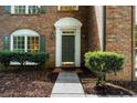 Close-up of the brick home's front entrance featuring manicured bushes and elegant window details at 11660 Windbrooke Way, Johns Creek, GA 30005