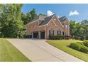 Long driveway leading to a brick home with an attached two-car garage and lush greenery at 3202 Lucky Pl, Conyers, GA 30013
