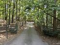 View of a long driveway with a stone and wooden fence leading to a home in a wooded area at 3355 Old Peachtree Rd, Dacula, GA 30019