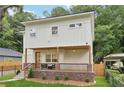 View of a two-story home featuring a welcoming front porch, landscaped yard, and a secure black fence at 1266 Elizabeth Sw Ave, Atlanta, GA 30310