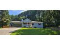 Well-maintained light blue house featuring a covered parking area, front porch, and lush green lawn at 2357 Whitehouse Rd, Dacula, GA 30019