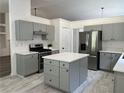Updated kitchen with gray cabinets, stainless appliances, an island, and stone countertops at 1570 Jami Hollow Way, Lawrenceville, GA 30043
