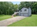 Two-story home with a two-car garage and a charming front porch, surrounded by green grass and trees at 174 Village Dr, Hiram, GA 30141