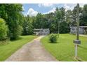 Long driveway leading up to a two-story home with gray siding and a two-car garage surrounded by tall trees at 174 Village Dr, Hiram, GA 30141