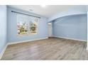 Well-lit living room with hardwood floors, large windows, and an arched entryway at 5430 Breckinridge Ln, Cumming, GA 30040