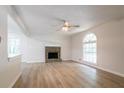 Bright living room with stone fireplace, light wood floors, ceiling fan, and a large arched window at 356 Waterway Trl, Powder Springs, GA 30127