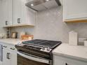 Close-up of a kitchen featuring a stainless steel range, white cabinetry, and herringbone backsplash at 1983 Deco Dr, Kennesaw, GA 30144
