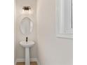 Compact powder room featuring a pedestal sink, round mirror, and modern lighting at 1995 Deco Dr, Kennesaw, GA 30144