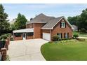 Rear view of brick home featuring a covered porch, attached garage, and spacious yard at 6310 Buckingham Pl, Cumming, GA 30040