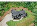 Aerial view of a dark modern farmhouse boasting a basketball court, lush lawn and wooded surroundings at 2100 Mountain Cove Ct, Woodstock, GA 30188