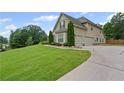 Side view of a tan two-story home showing a well-manicured lawn and a wide driveway at 108 Donovan Ave, Locust Grove, GA 30248